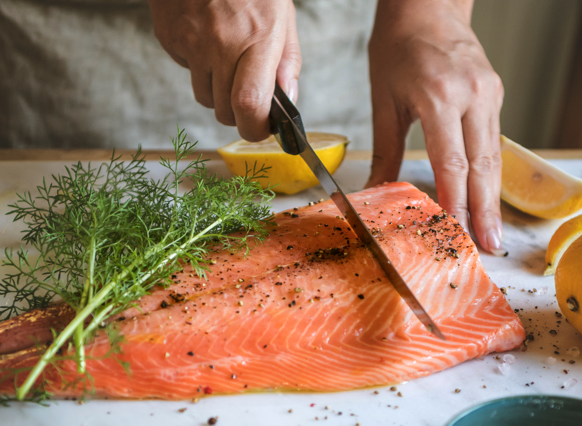 person slicing fresh salmon dill lemon - In keeping with a Dietitian, Incorporate These 5 Meals into Each Meal to Velocity Up Weight Loss